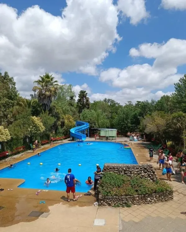 Piscina exterior con tobogán azul y áreas verdes alrededor