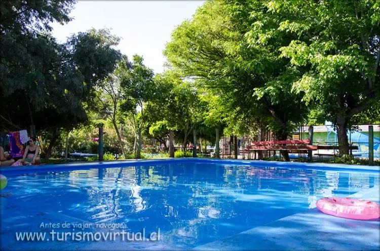 Piscina exterior rodeada de árboles y sectores de descanso